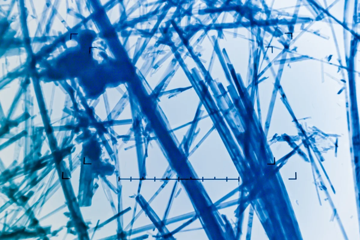 Magnified blue asbestos fibres viewed through laboratory microscopy.