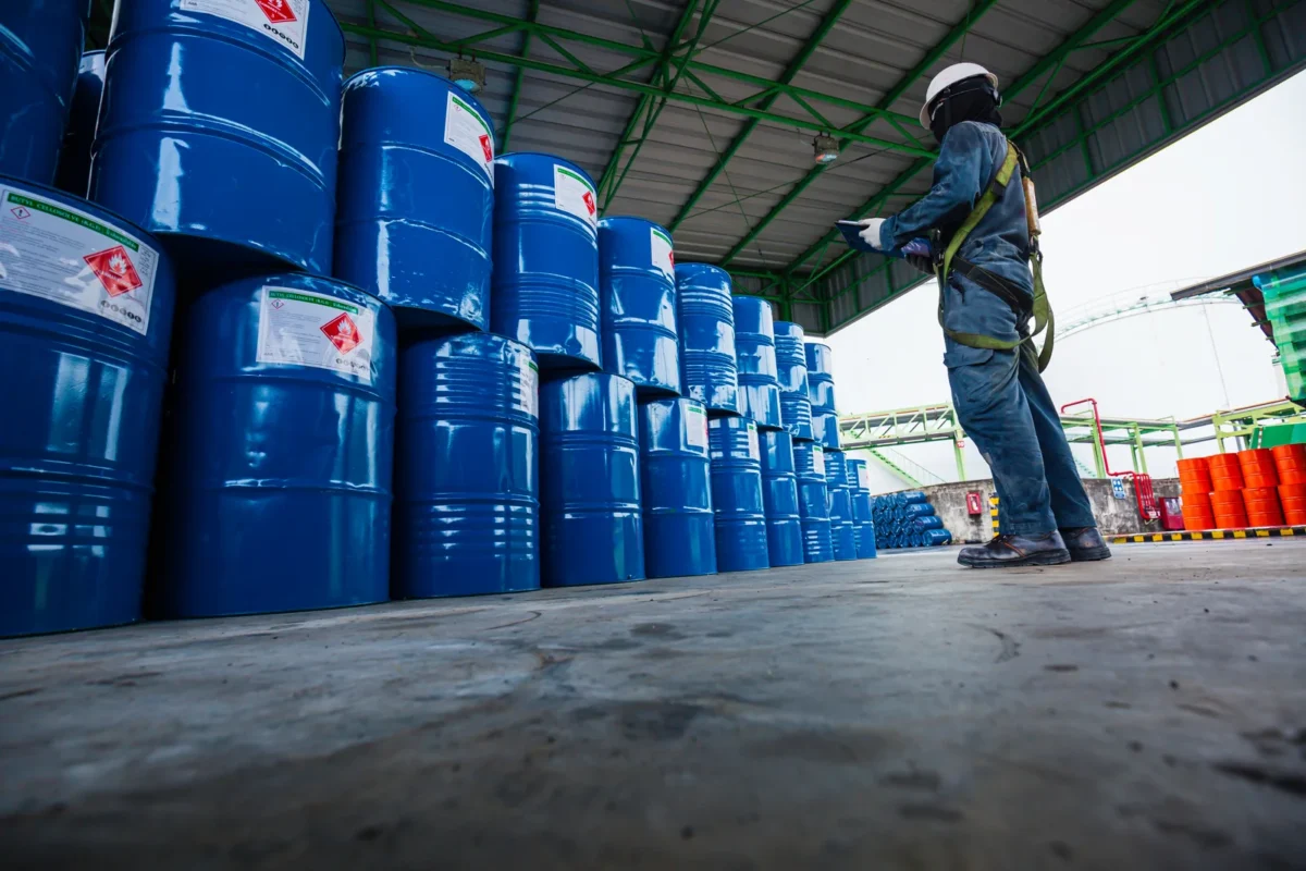 Inspecting blue industrial drums in a chemical storage warehouse.