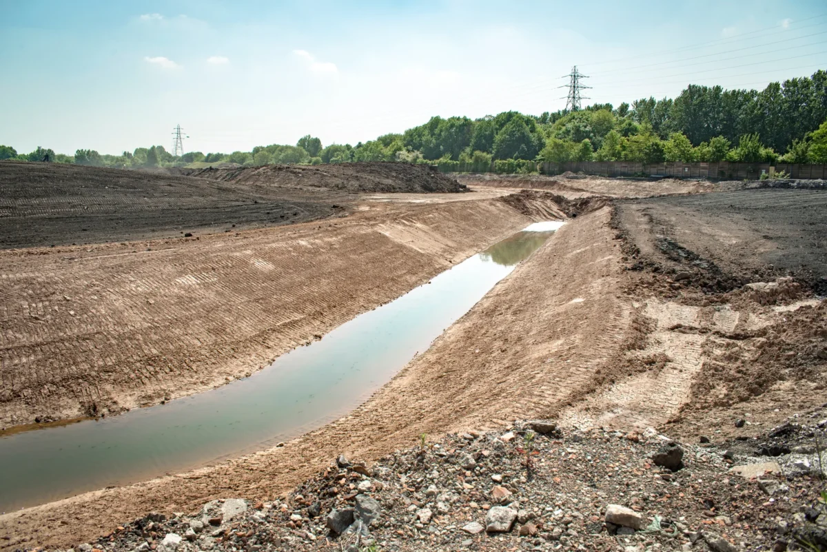 Prepared ground and a water channel at a former industrial site undergoing remediation.