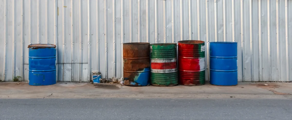 Used steel drums awaiting collection beside an industrial building.